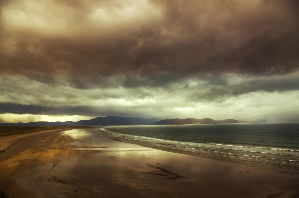 Stormy skies over Dingle Peninsula's golden beach, where selkie legends and Irish mythology come alive.
